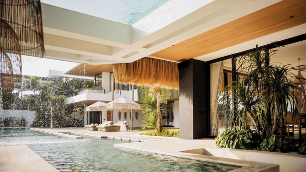 Un área de piscina exterior moderna con sillones de descanso y una cascada.