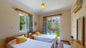 A room with two beds, a desk, a chair, and a balcony with curtains. - Villa Katerina in Neo Chorio (Neo Chorio)