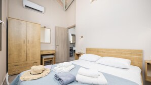 Et hotelværelse med seng, garderobeskab, spejl, badeværelselementer og aircondition.