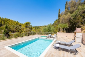 A rectangular swimming pool with clear blue water, surrounded by a wooden deck. There are lounge chairs and a barbecue area. - Villa Sia in Ionian Islands (Kefalonia)