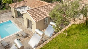 Una villa con piscina, mobiliario exterior y paneles solares.