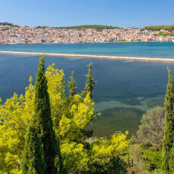 A coastal cityscape with a clear view of the sea and a densely built urban area in the background.