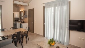 Una cocina moderna con electrodomésticos, un comedor con mesa y sillas, y una sala de estar con televisor y cortinas.