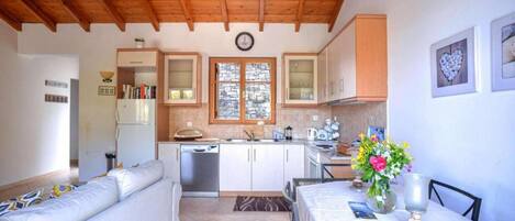 Una cocina acogedora con vigas de madera, un comedor con mesa y sillas, y un sofá.