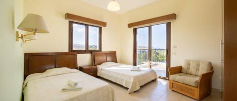 A hotel room with two beds, a sofa, a balcony, and a view of the city.