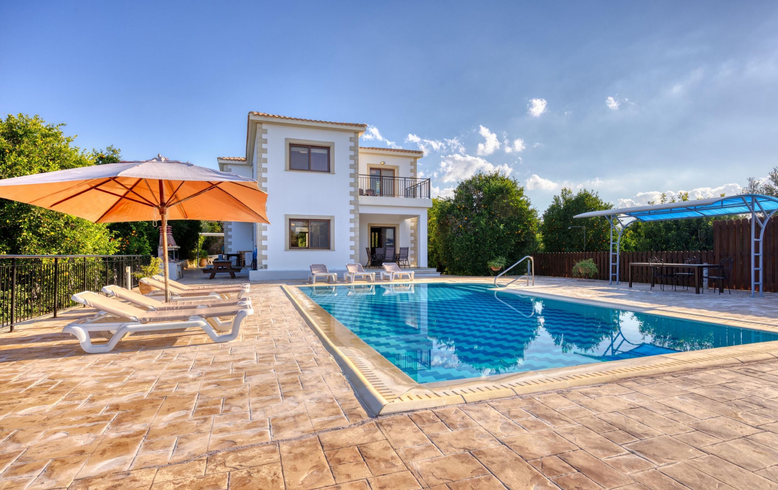 A two-story house with a swimming pool, outdoor furniture, and umbrellas.