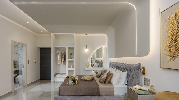 Une chambre moderne avec un grand lit, des tables de chevet, une armoire et une salle de bain visible à travers une porte ouverte.