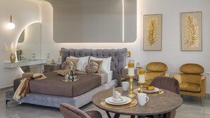 Une chambre moderne avec un grand lit, des tables de chevet, une table à manger ronde et deux fauteuils.