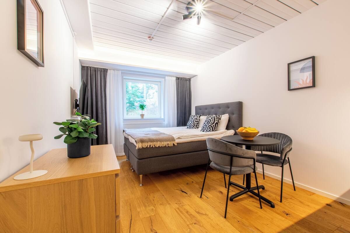 Un dormitorio con cama, mesita de noche, silla y una pequeña mesa con un frutero.