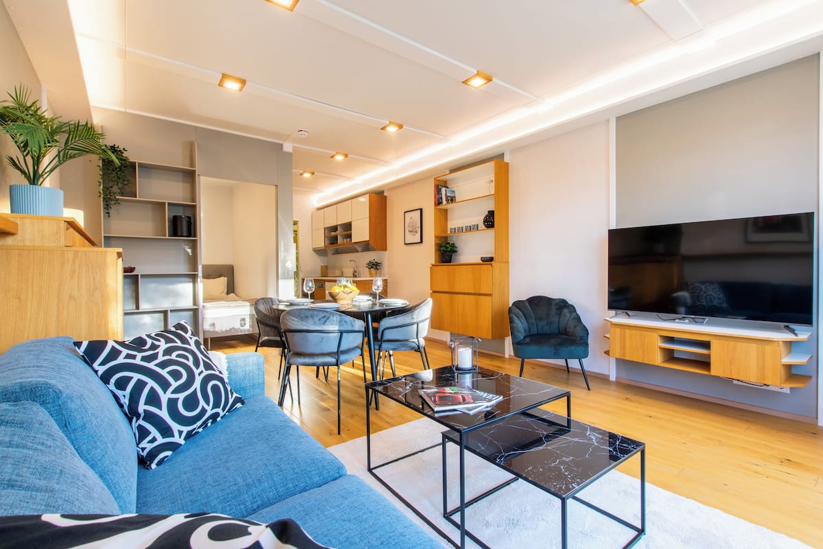 Una sala de estar moderna con sofá, mesa de centro y mueble para televisión.