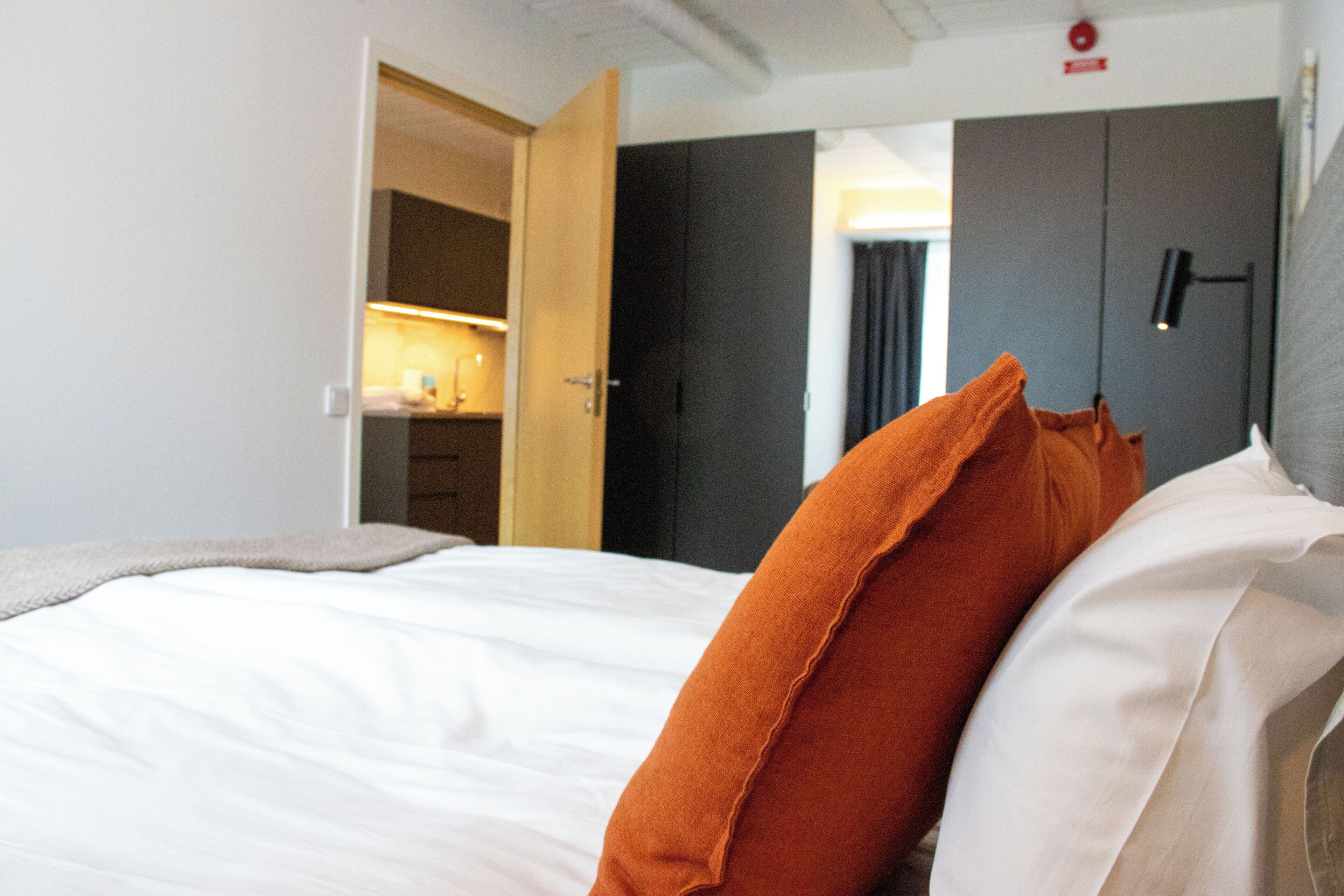 A hotel room with a bed, a wardrobe, and a door leading to a bathroom.