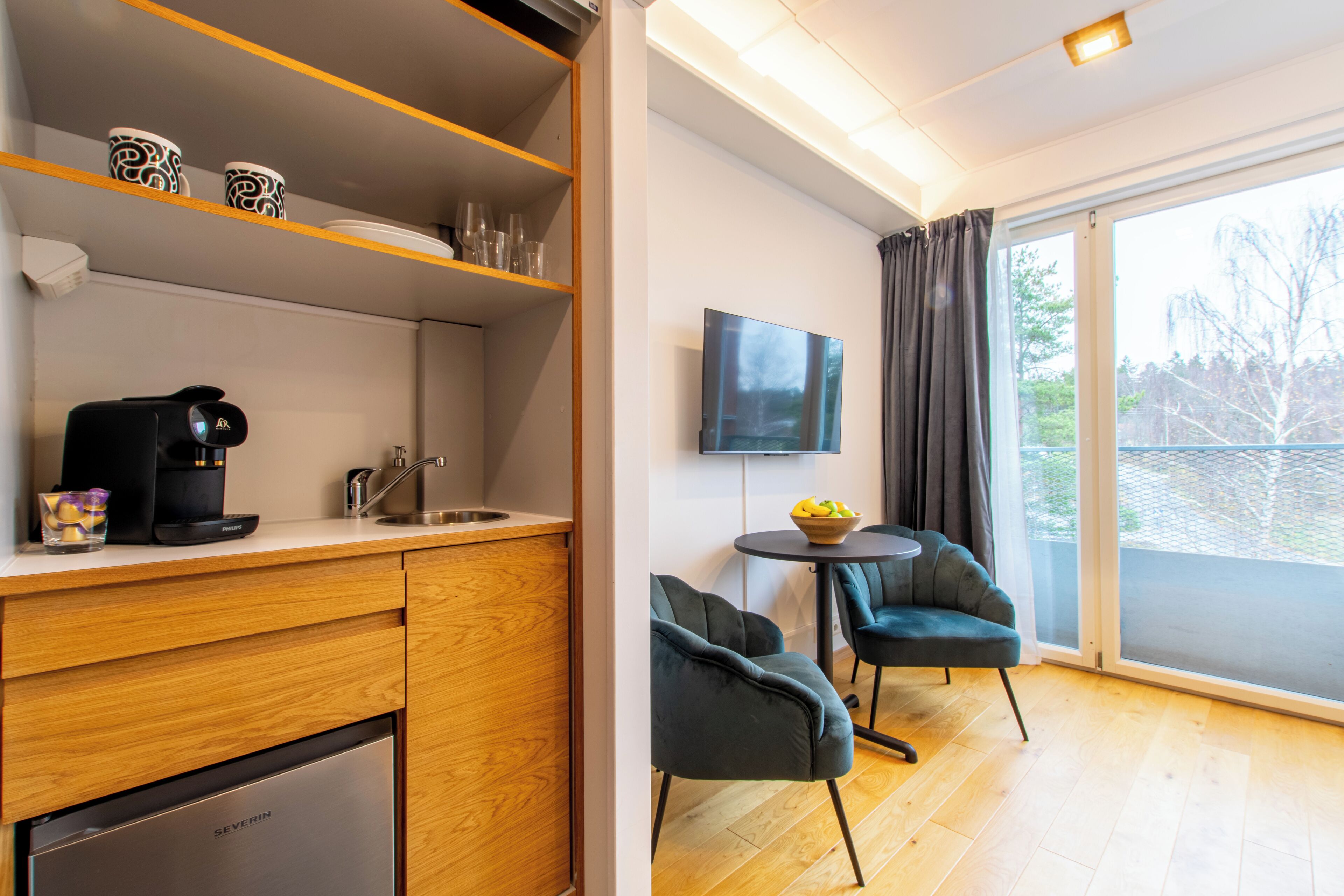 A modern kitchen with a dishwasher, a coffee machine, and a dining area with two chairs and a small table.