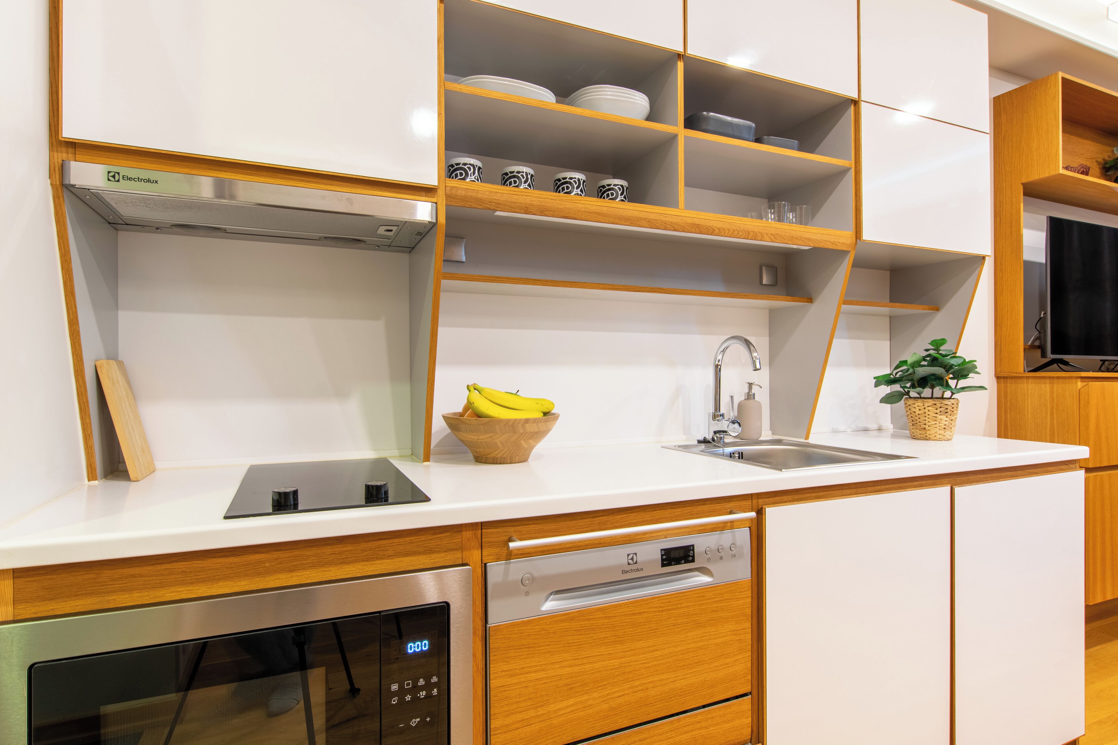 Une cuisine moderne avec des meubles blancs, des étagères en bois et un lave-vaisselle encastré.