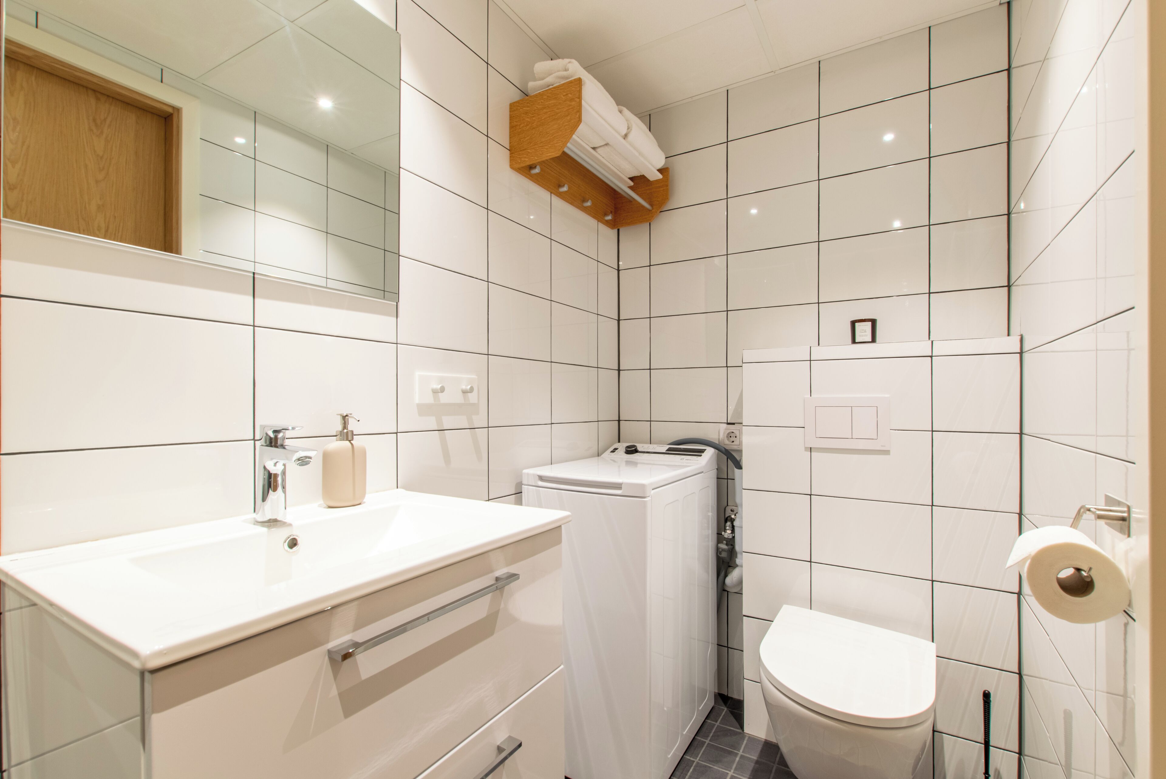 A modern bathroom with a white sink, mirror, and toilet.