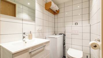 A modern bathroom with a white sink, mirror, and toilet.