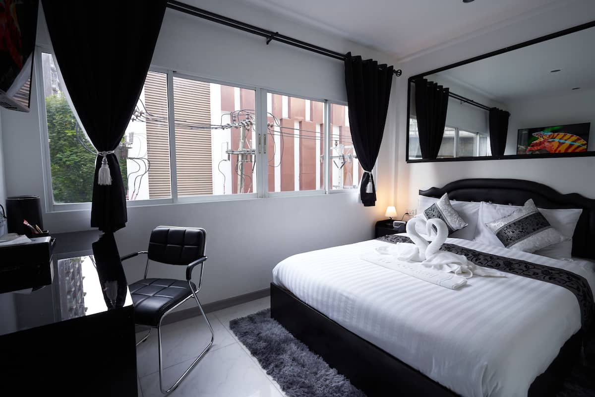 Quarto de hotel moderno com uma cama grande, uma mesa e uma cadeira.