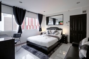A modern bedroom with a large bed, a desk, and a chair. - Thonglor Suites Hotel (Bangkok)