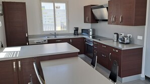 A modern kitchen with dark wood cabinets, a white countertop, a built-in microwave, and a coffee maker. - Offre de Lancement ! Villa Nice Centre (Nice)