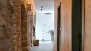 A corridor with stone walls, wooden doors, and a tiled floor. - Villa Vittorina (Pusti)