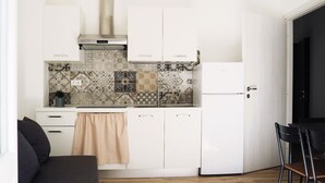 Una cocina pequeña con armarios blancos, un salpicadero con diseño y una toalla color beige colgada en la puerta del horno.