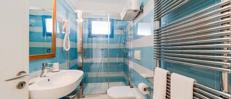 Un baño con cabina de ducha de vidrio, un lavamanos blanco y un inodoro.