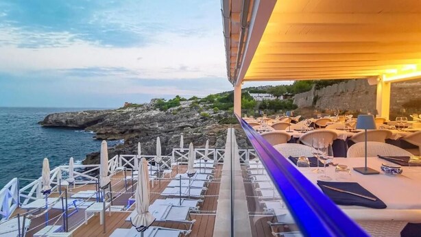 A deck with sun loungers and umbrellas, overlooking a rocky coastline. - Lo Scalo bed and breakfast (Alessano)