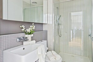 A modern bathroom with a white sink, toilet, and shower.