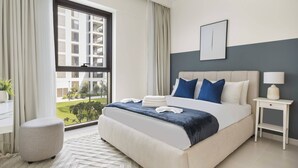 A modern hotel room with a large bed, a bedside table with a lamp, a view of a building outside, and a window with curtains. - Silkhaus Summer Towers Creek Harbour (Dubai)