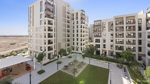 A modern apartment complex with multiple buildings, outdoor seating areas, and a landscaped courtyard. - Silkhaus Summer Towers Creek Harbour (Dubai)