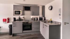 A compact kitchen with built-in appliances, a sink, and a fire extinguisher. - Cozy 1-BR | Steps from Liverpool Centre (Liverpool)