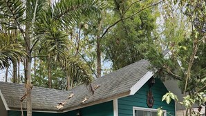 A small, single-story house with a green exterior and white trim. It features a front porch with a bench and a small table. - Baan Rai Somkiat Homestay (Pak Chong)