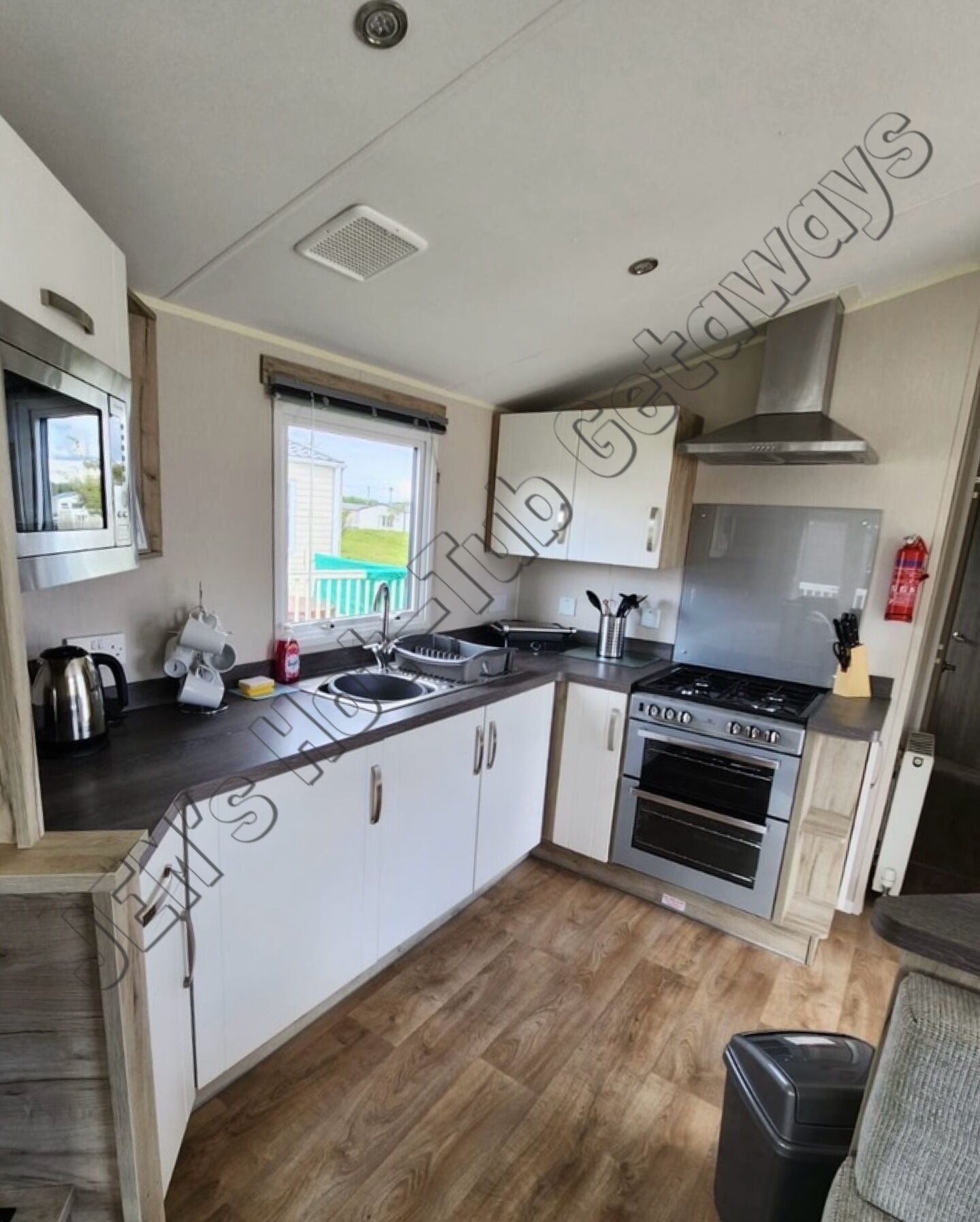 A compact kitchen with a stove, oven, sink, and cabinets. - 6 Berth luxury holiday home at Tattershall Lakes. Private Hot-Tub. Pet Friendly (Lincoln)