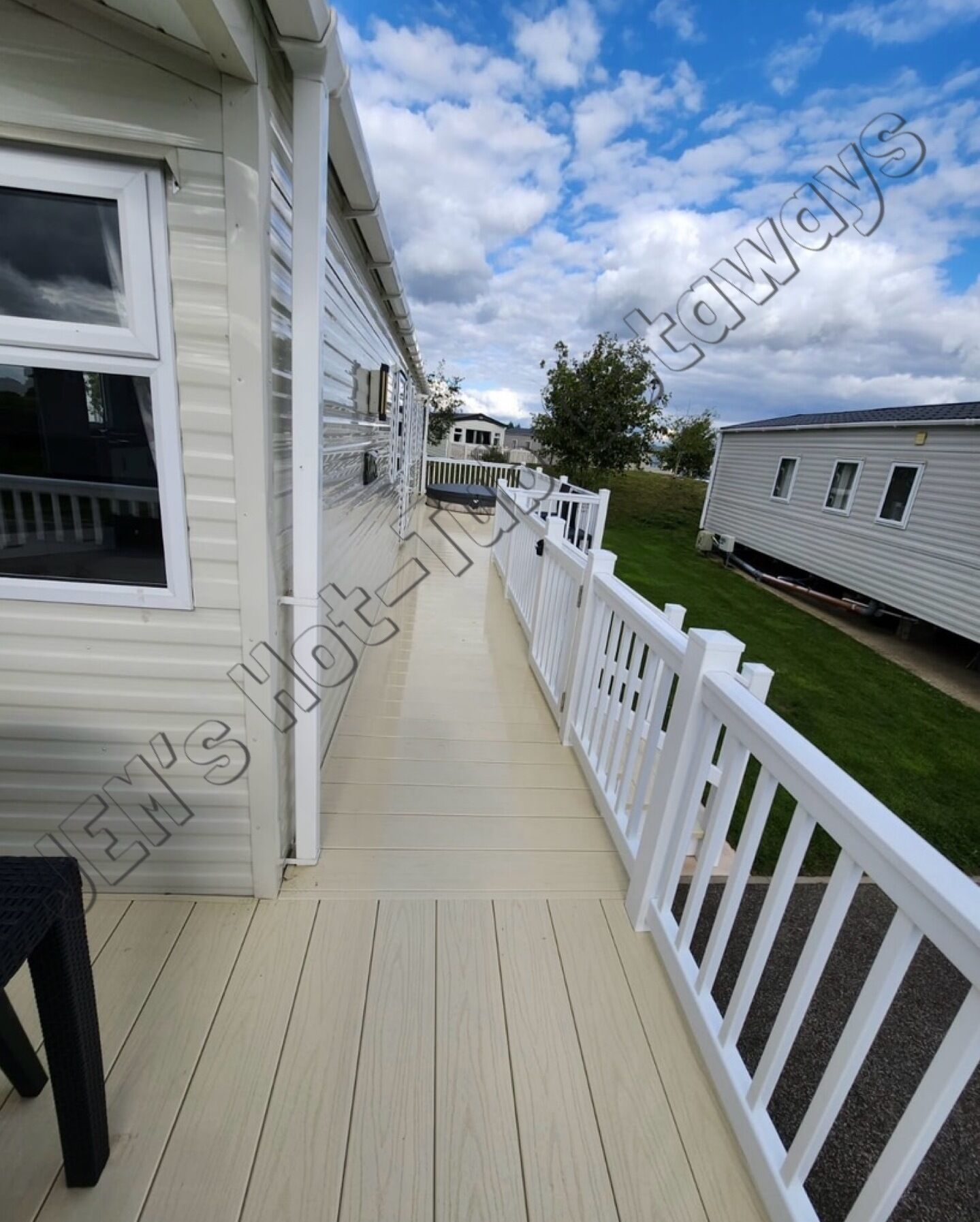 A covered porch with a white railing, leading to a grassy yard.