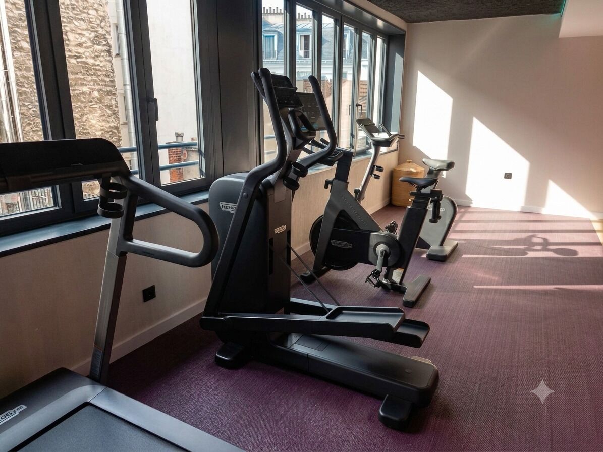 A gym with treadmills and exercise bikes, large windows, and a purple carpet.