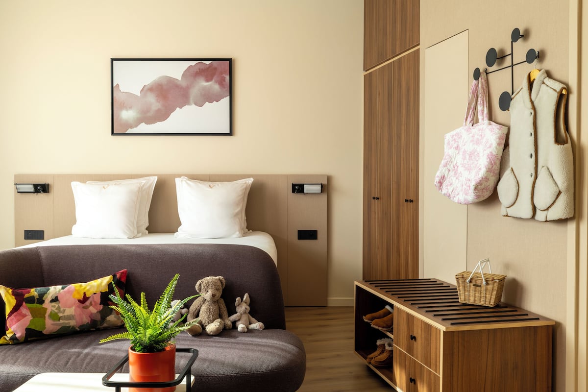 A modern bedroom with a bed, a sofa, a potted plant, and a wall-mounted shoe rack.