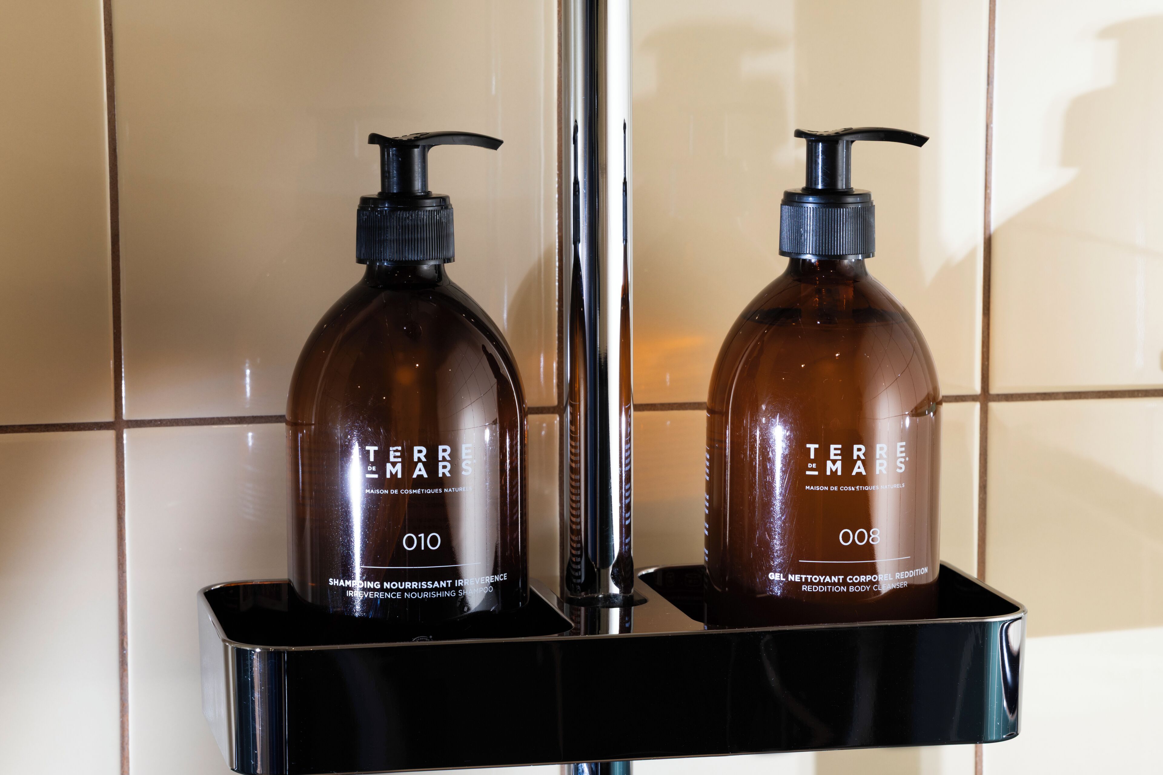 Two bottles of Terre Mars shampoo and body wash on a black soap dish.
