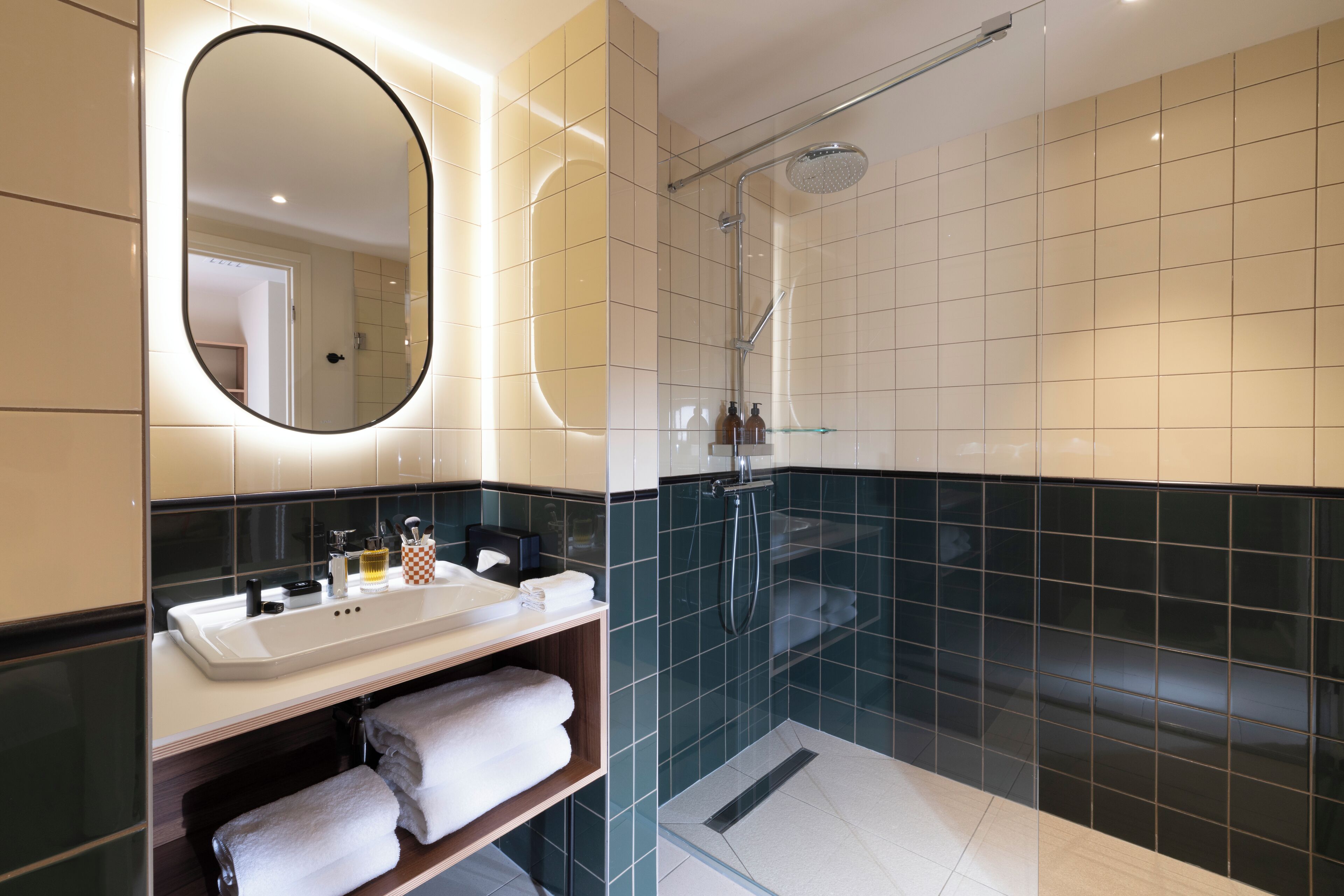 A modern bathroom with a large mirror, a sink with toiletries, and a glass-enclosed shower area.