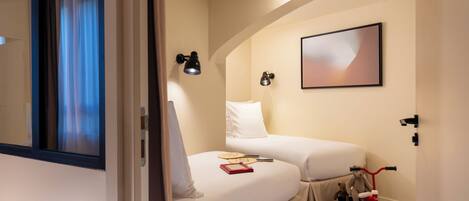 A hotel room with two beds, a small table with a book and a toy, and a toy car.