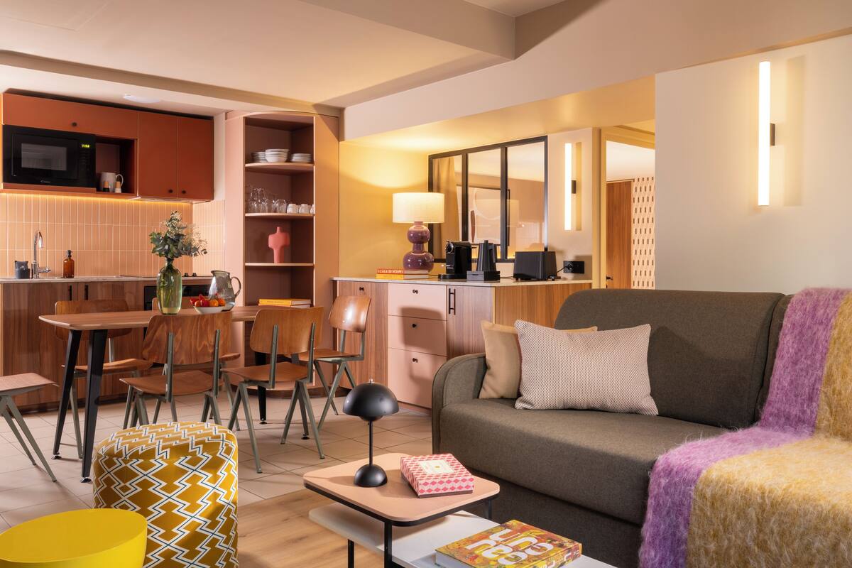 A modern living room with a sofa, a coffee table, and a dining area with chairs and a table.