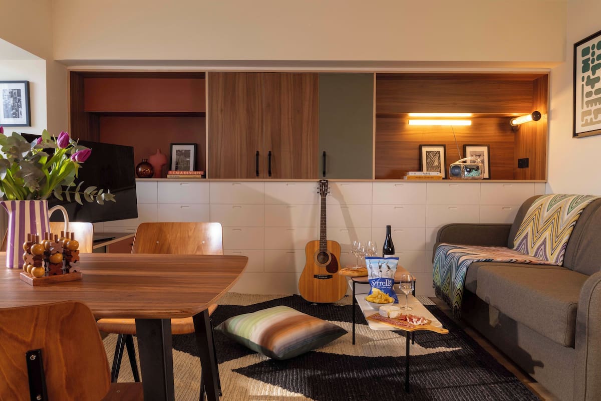 A cozy living room with a wooden dining table, a sofa, and a guitar.