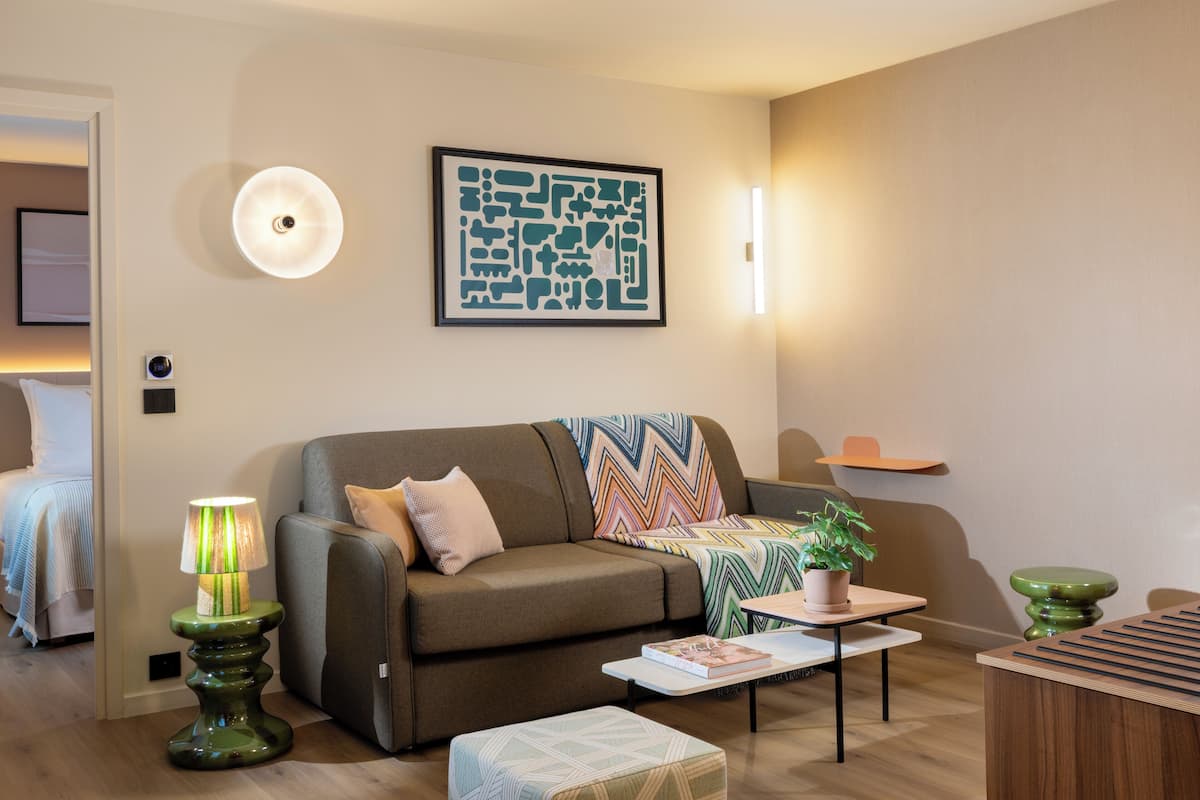 A modern living room with a sofa, a coffee table, a lamp, and a framed artwork on the wall.