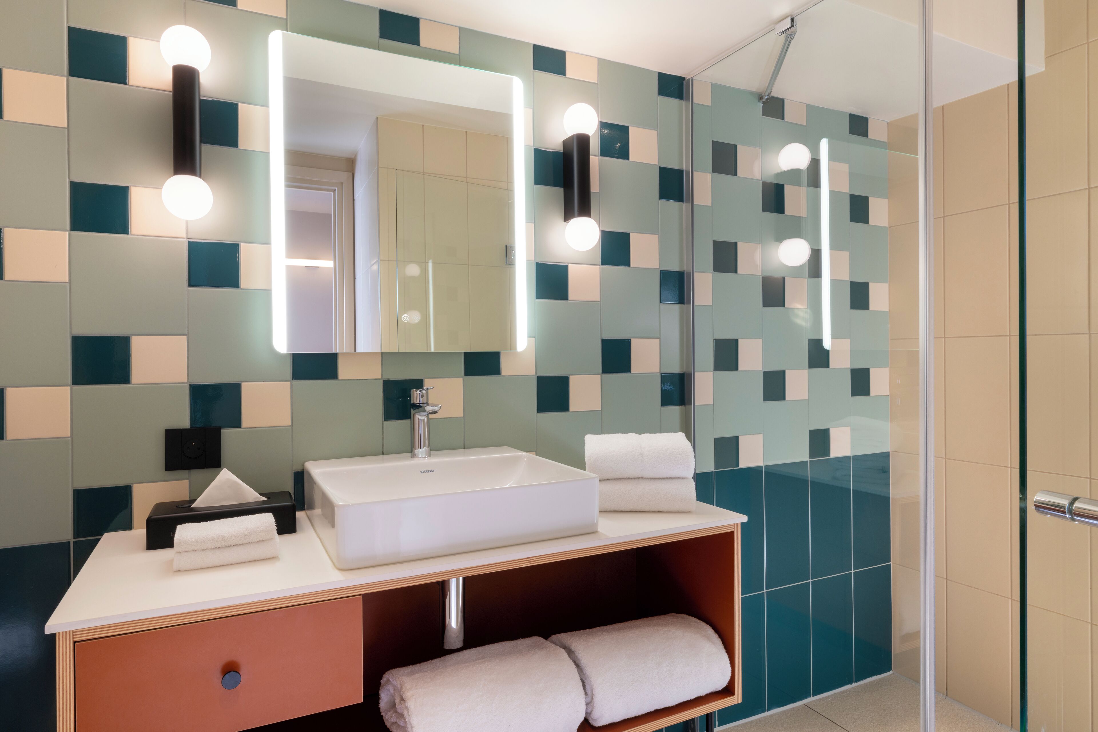 A modern bathroom with a white sink, mirror, and towel rack.