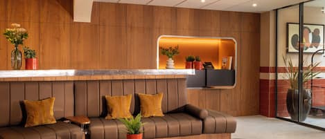 A modern reception area with a leather sofa, a glass coffee table, and a green armchair.