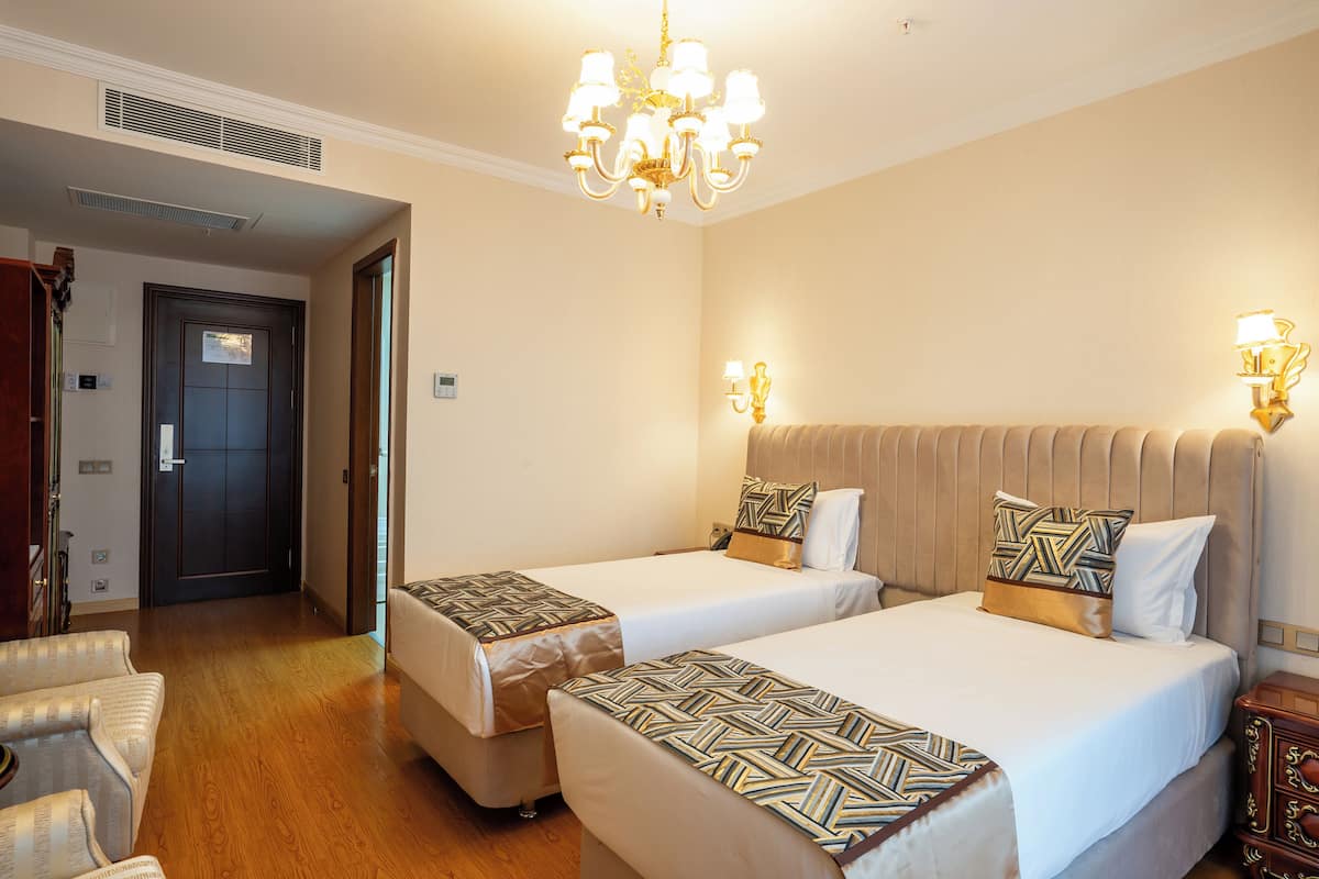 Ein Hotelzimmer mit zwei Betten, einer Chandelieber und Holzboden.