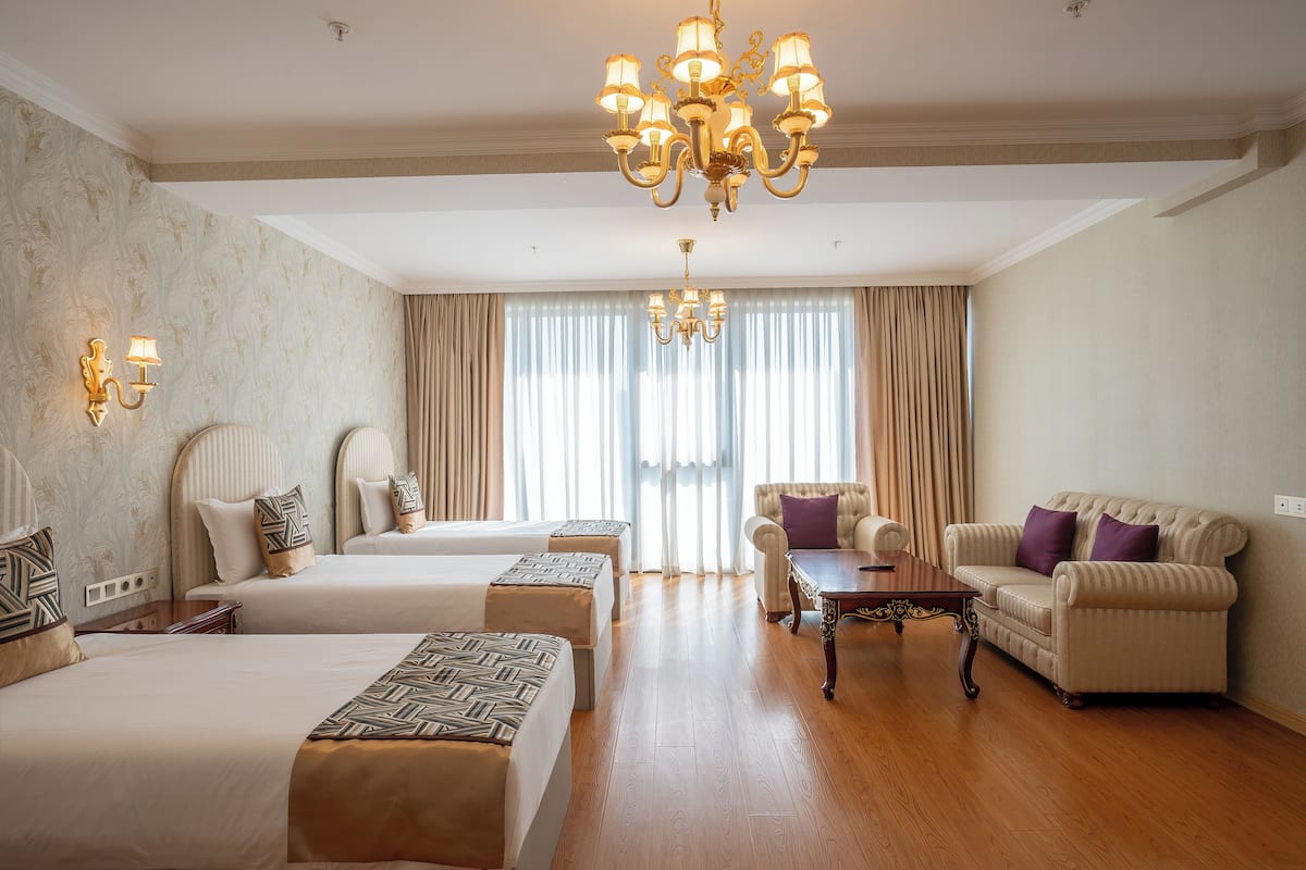 Ein Hotelzimmer mit zwei Betten, einer Couch, einem Couchtisch und einer Kristallleuchtre.