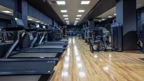Ein Fitnessraum mit Laufbändern, Kraftgeräten und Holzboden.