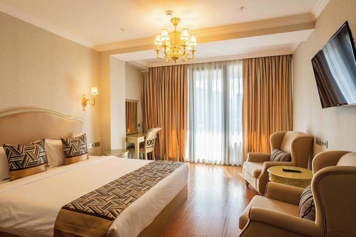 Ein Hotelzimmer mit einem großen Bett, einem Schreibtisch, einem Sessel, einer Couch und einem Fernseher.