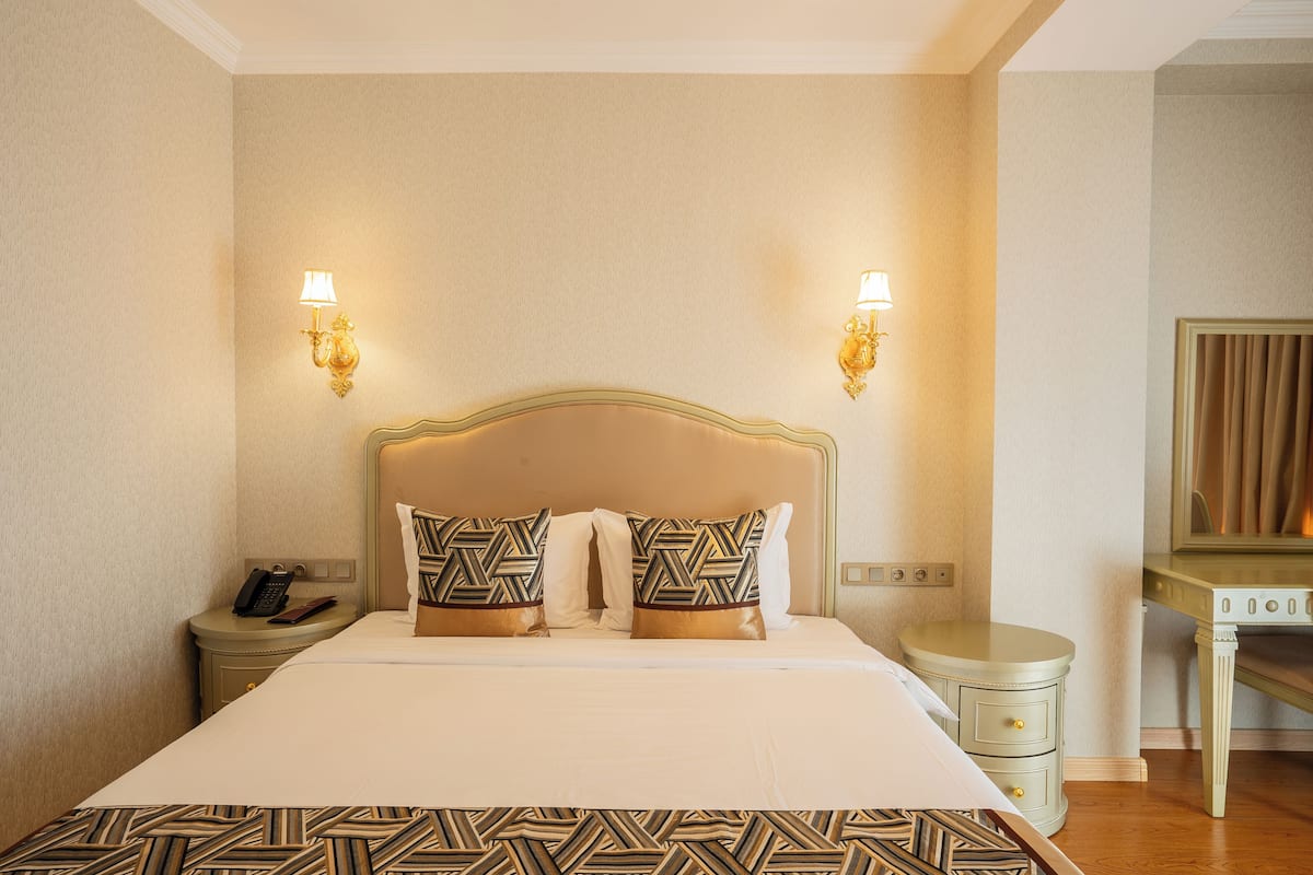 Ein Hotelzimmer mit Bett, Nachttischlampen, einem Nachttisch, einem Schreibtisch und einem Spiegel.