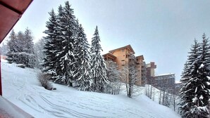 Una pista da sci innevata con un chalet in legno e alberi.