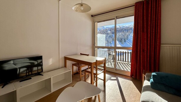 A modern living room with a TV, a dining table, and a sofa.